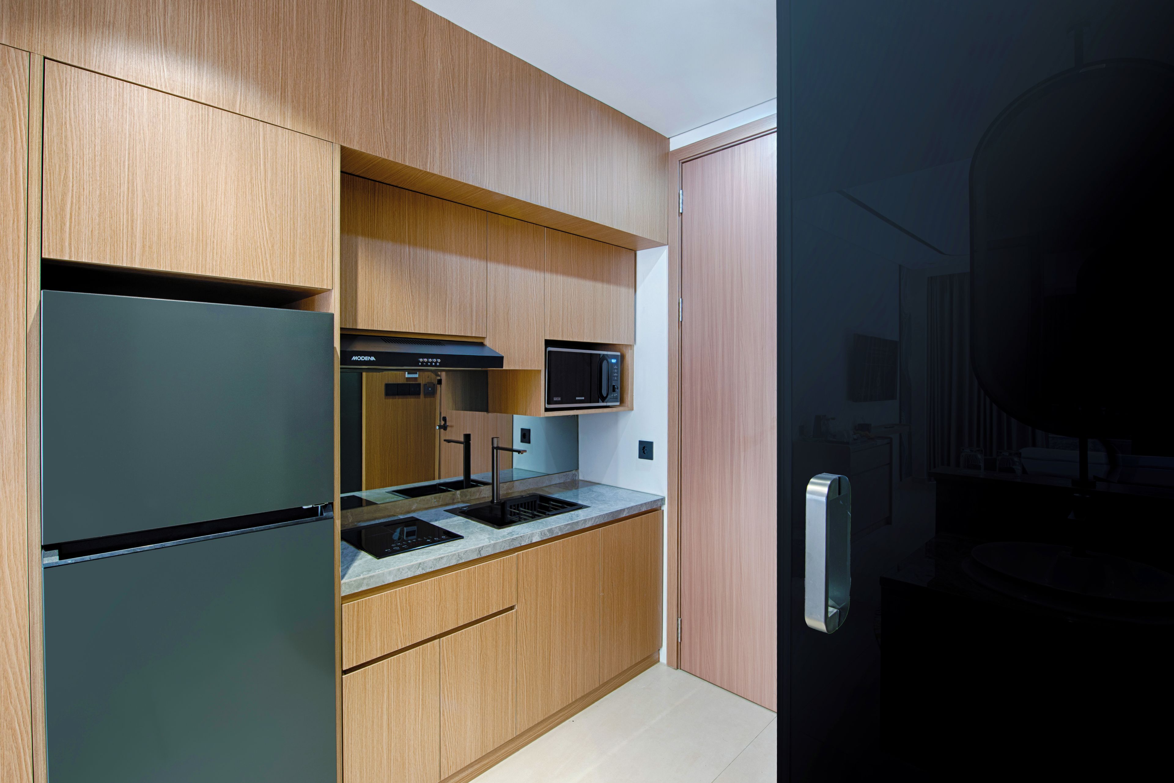 A modern kitchen with wooden cabinets, a built-in microwave, and a stainless steel refrigerator.