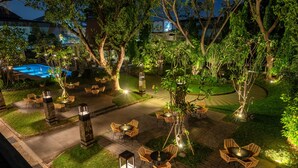 An outdoor patio area with wicker furniture, stone pillars, and a swimming pool in the background. - Oakwood Hotel & Apartments Taman Mini Jakarta (Jakarta)