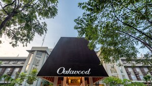 A hotel with a prominent "Oakwood" sign, modern architecture, and a well-maintained garden. - Oakwood Hotel & Apartments Taman Mini Jakarta (Jakarta)