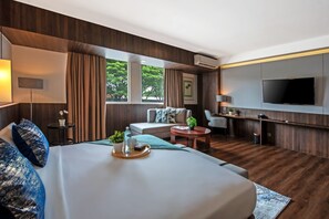 A modern hotel room with a large bed, a sofa, a TV, and a dining area. - Oakwood Hotel & Apartments Taman Mini Jakarta (Jakarta)