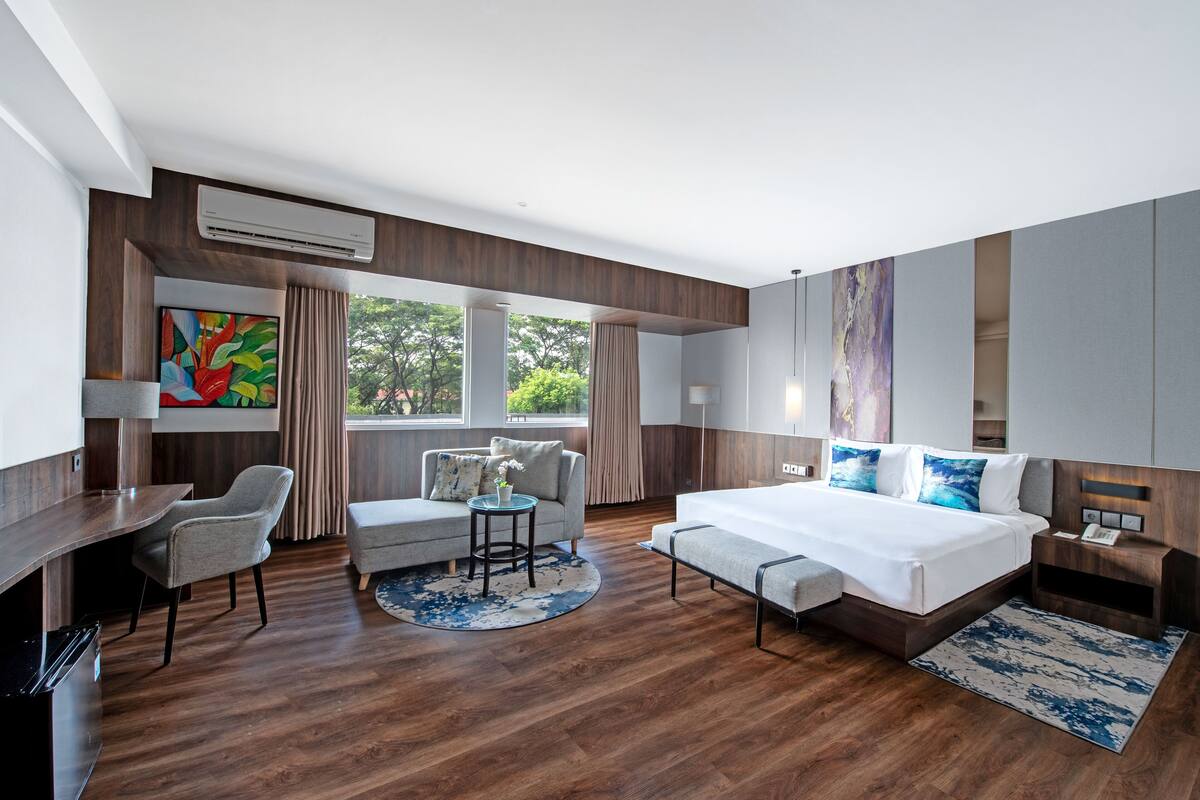 Ein modernes Hotelzimmer mit einem großen Bett, einer Couch, einem Schreibtisch und einer Essecke.