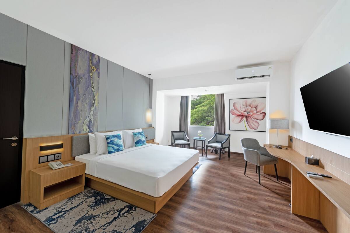 Ein modernes Hotelzimmer mit einem großen Bett, Nachttischen, einem Schreibtisch und einem Fernseher.