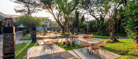 An outdoor patio area with stone pillars, wicker furniture, and a paved walkway.