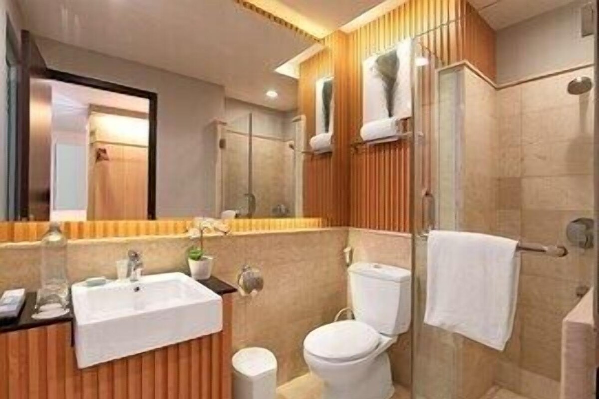 Un baño moderno con tocador de madera, cabina de ducha de vidrio y un inodoro blanco.