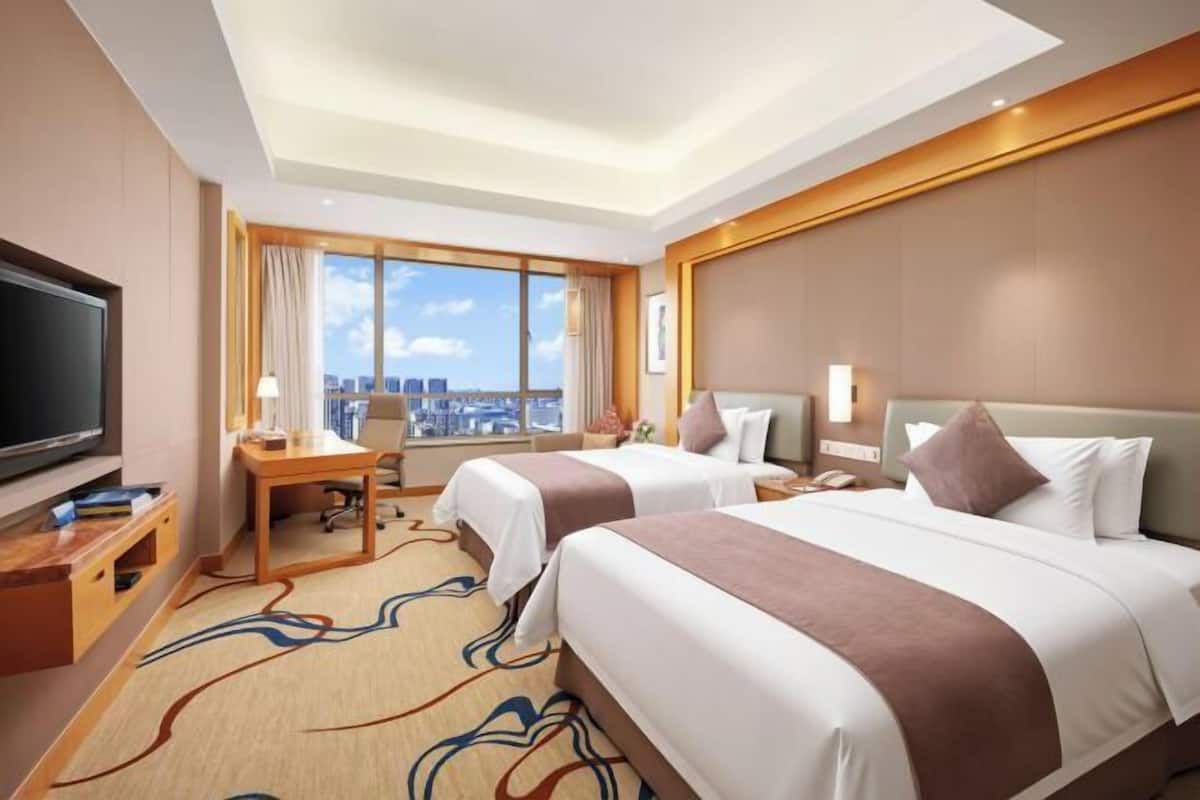 Une chambre d’hôtel avec deux lits, un bureau, une télévision et une vue sur la ville.