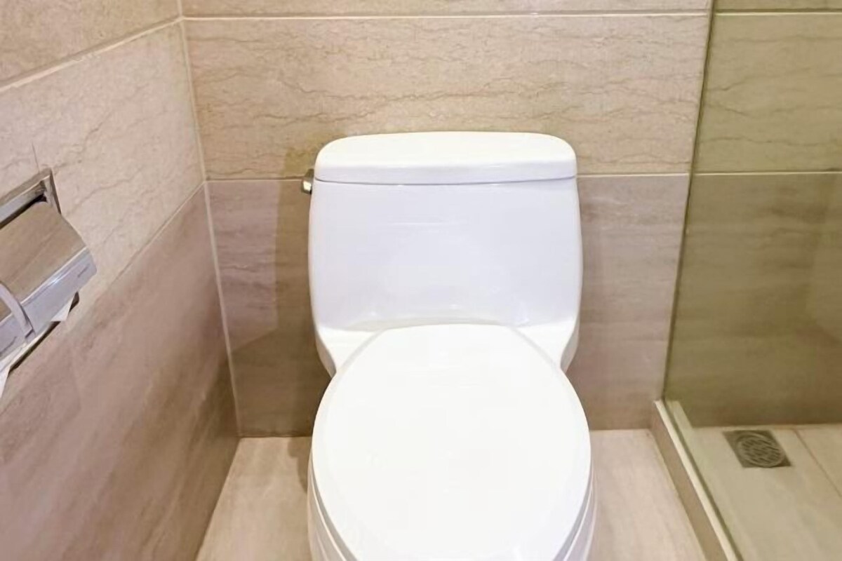 A white toilet in a bathroom with tiled walls and a shower area.