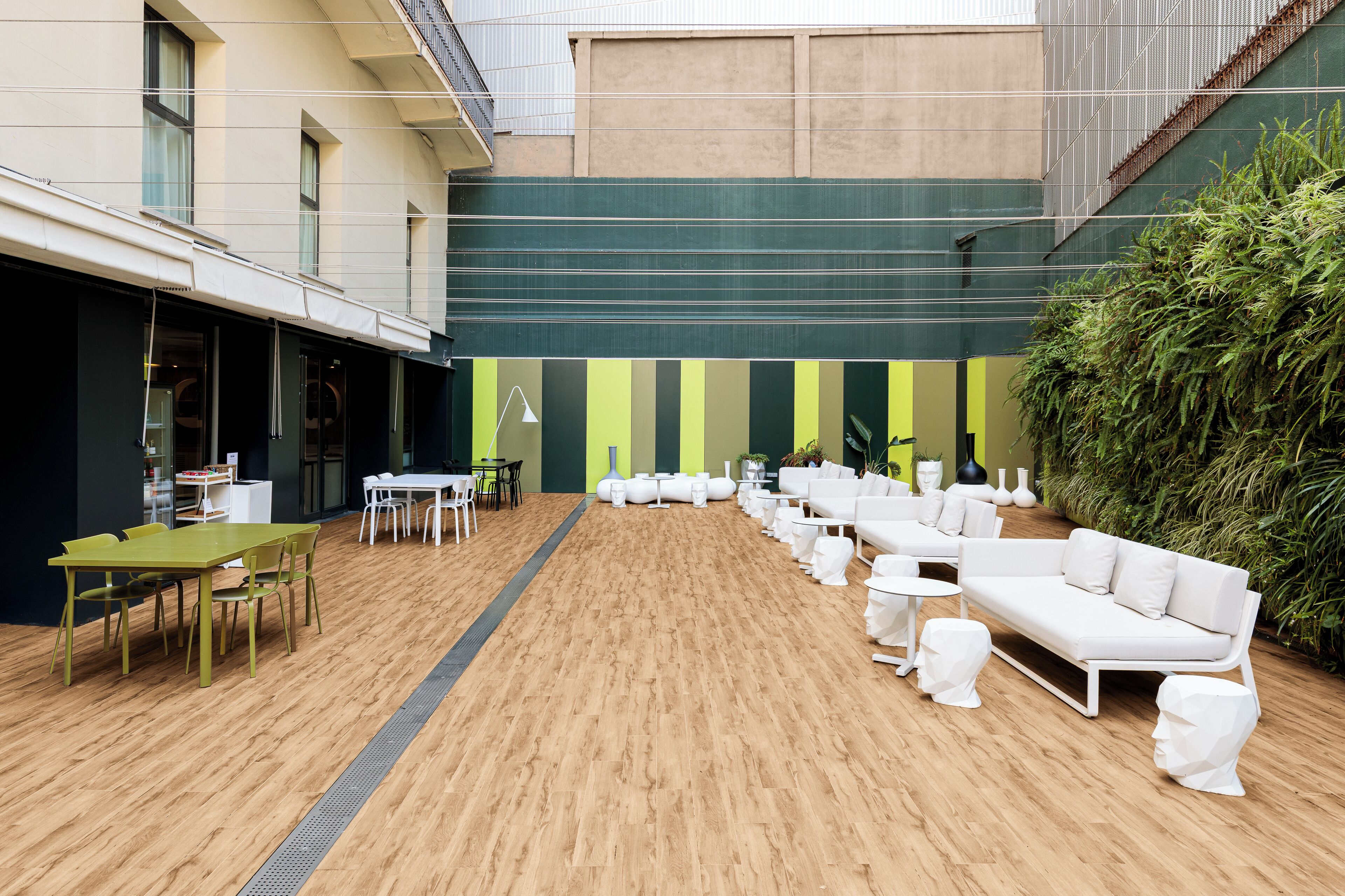 Un espace extérieur moderne aménagé avec des tables et des chaises, un canapé et une grande plante verte.