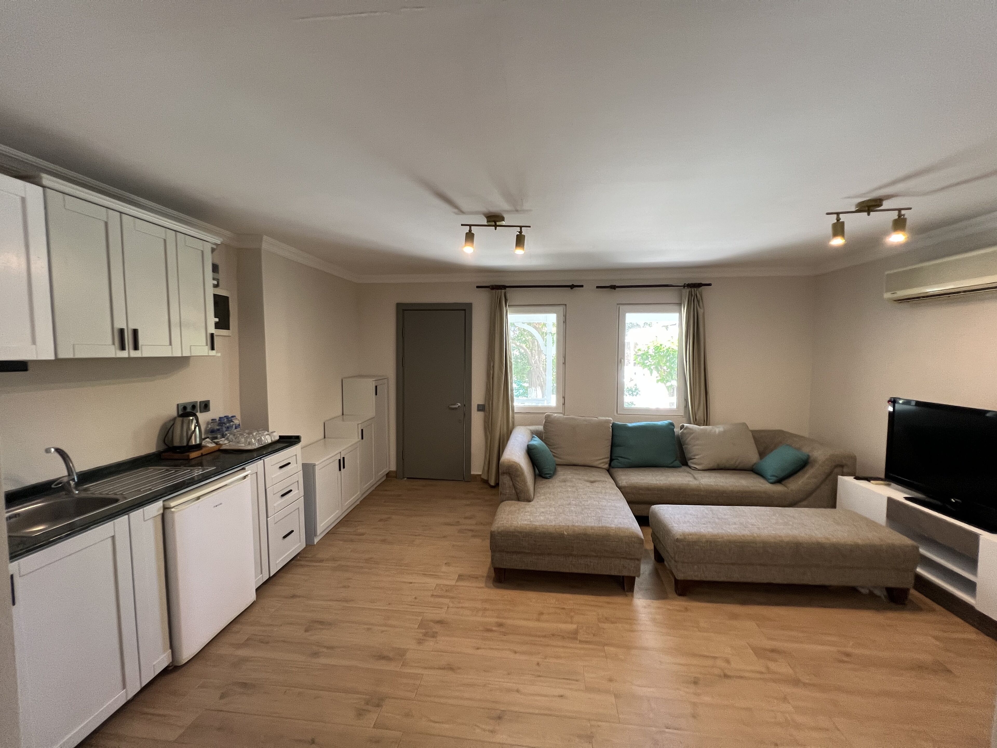 Ett kompakt bostadsutrymme med ett litet kök, en soffgrupp och en TV.