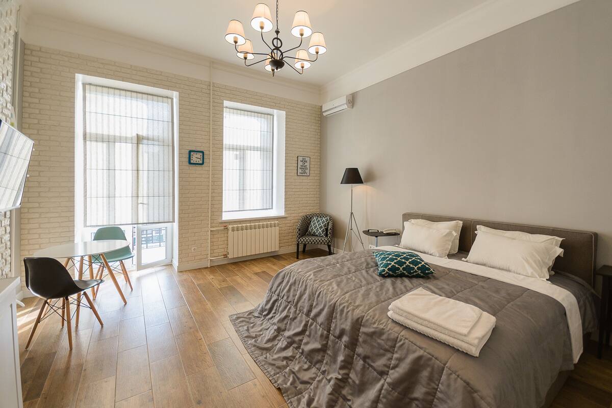 Un dormitorio con una cama grande, una silla, una mesa y un ventanal.