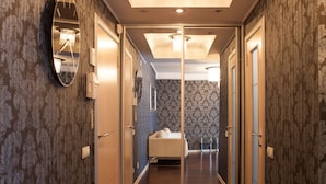 A hallway with a mirrored wall, a chandelier, and a bed in the adjacent room. - Partner Guest House Saksahans'koho (Kyiv)