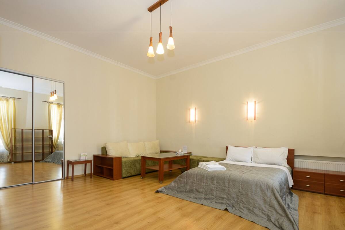 Un dormitorio con cama, mesita de noche, cómoda, espejo y suelo de madera.
