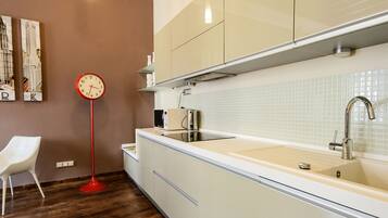 A modern kitchen with white cabinets, a stainless steel sink, and a red floor lamp.