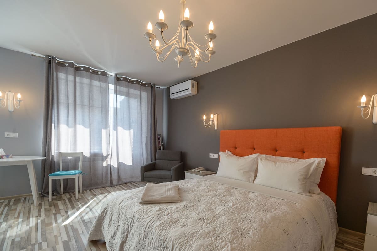 Habitación de hotel con una cama grande, un escritorio, una silla y una araña.