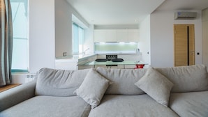 A modern living room with a grey sofa and a glass dining table in the background. - Partner Guest House Saksahans'koho (Kyiv)