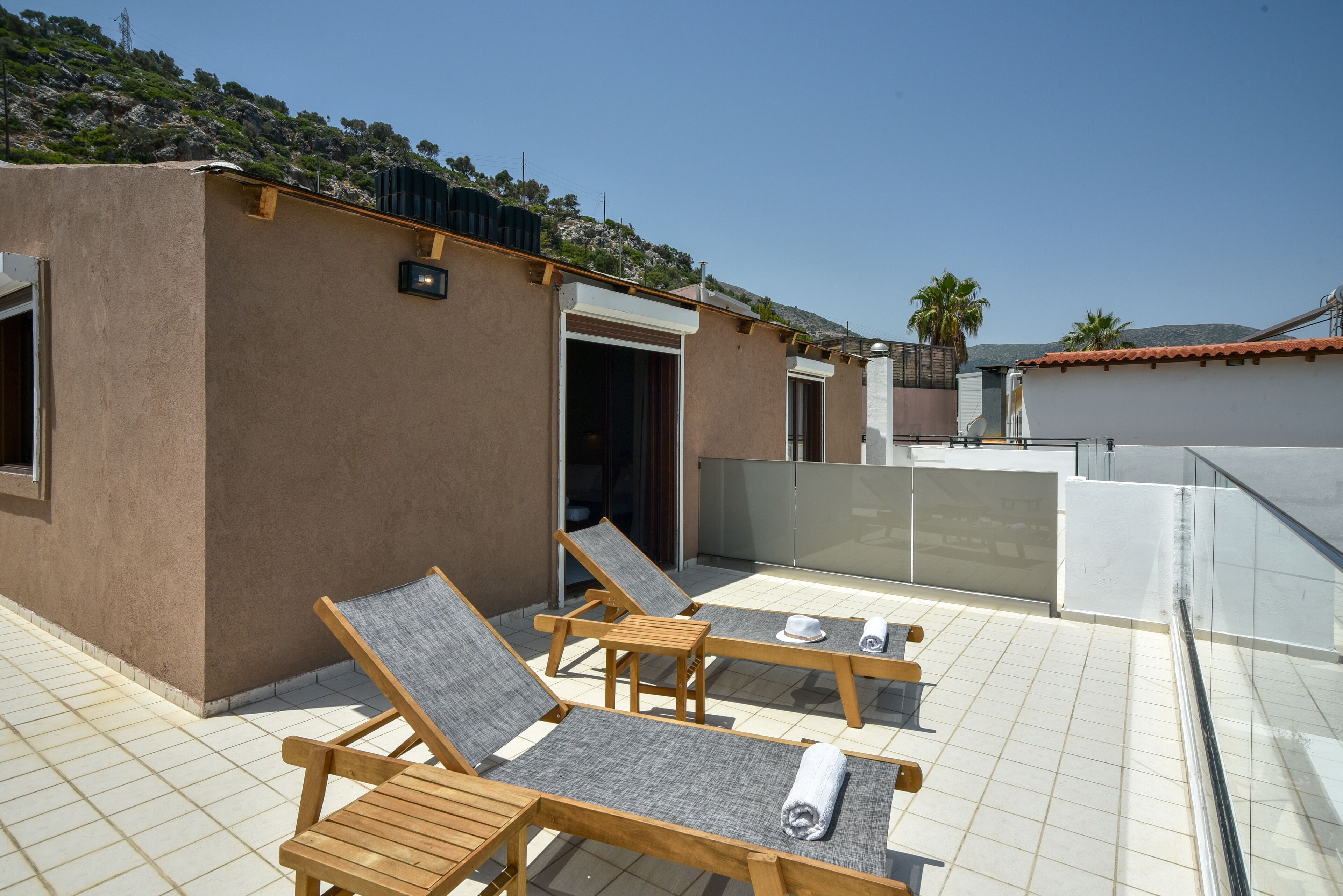 Una terraza en la azotea con dos sillones de madera, un edificio pequeño y vistas del paisaje circundante.
