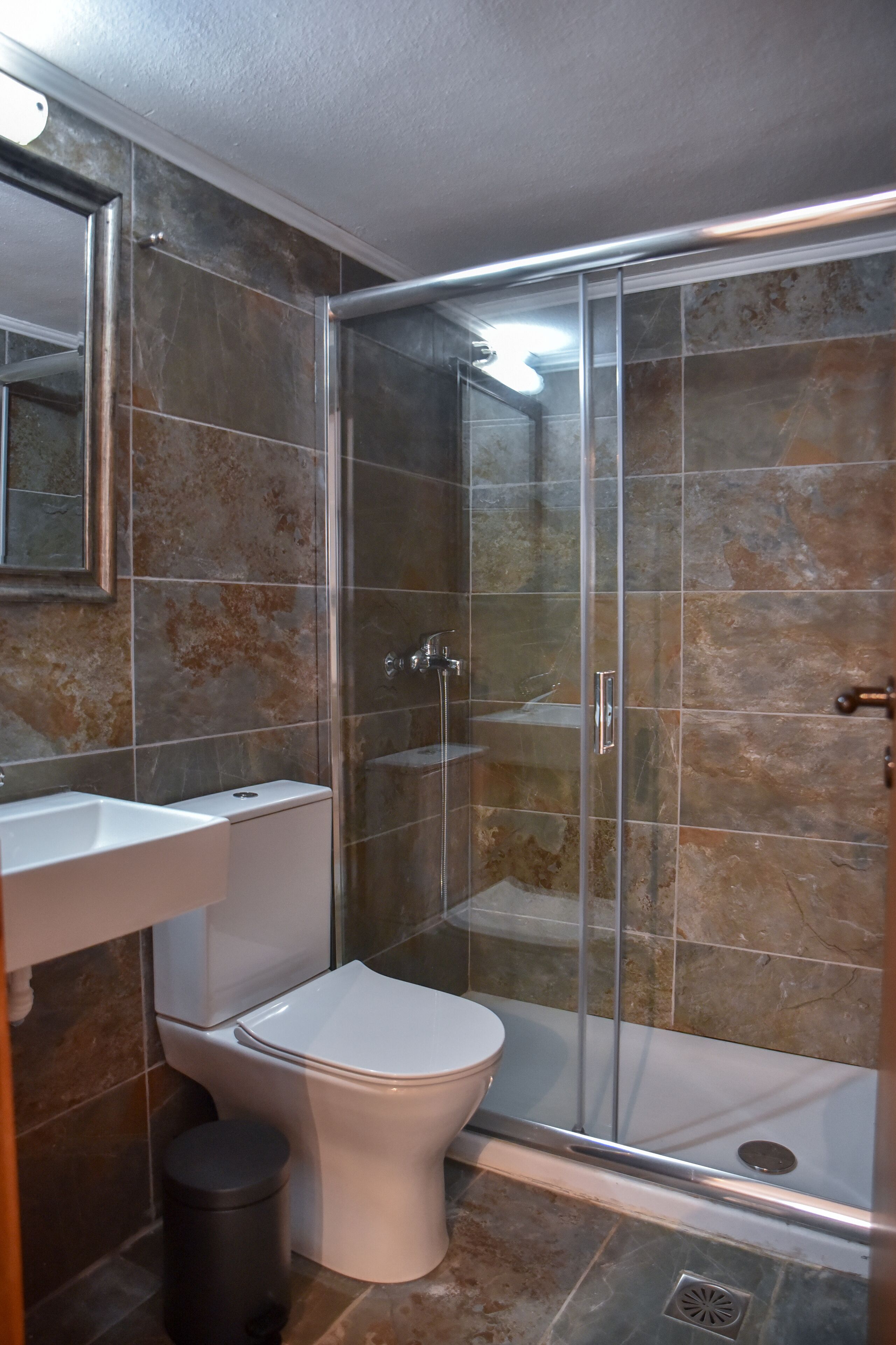 Ein Badezimmer mit Duschkabine, Toilette und Waschbecken.