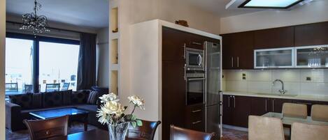 A modern kitchen with dark cabinetry, stainless steel appliances, and a large window.