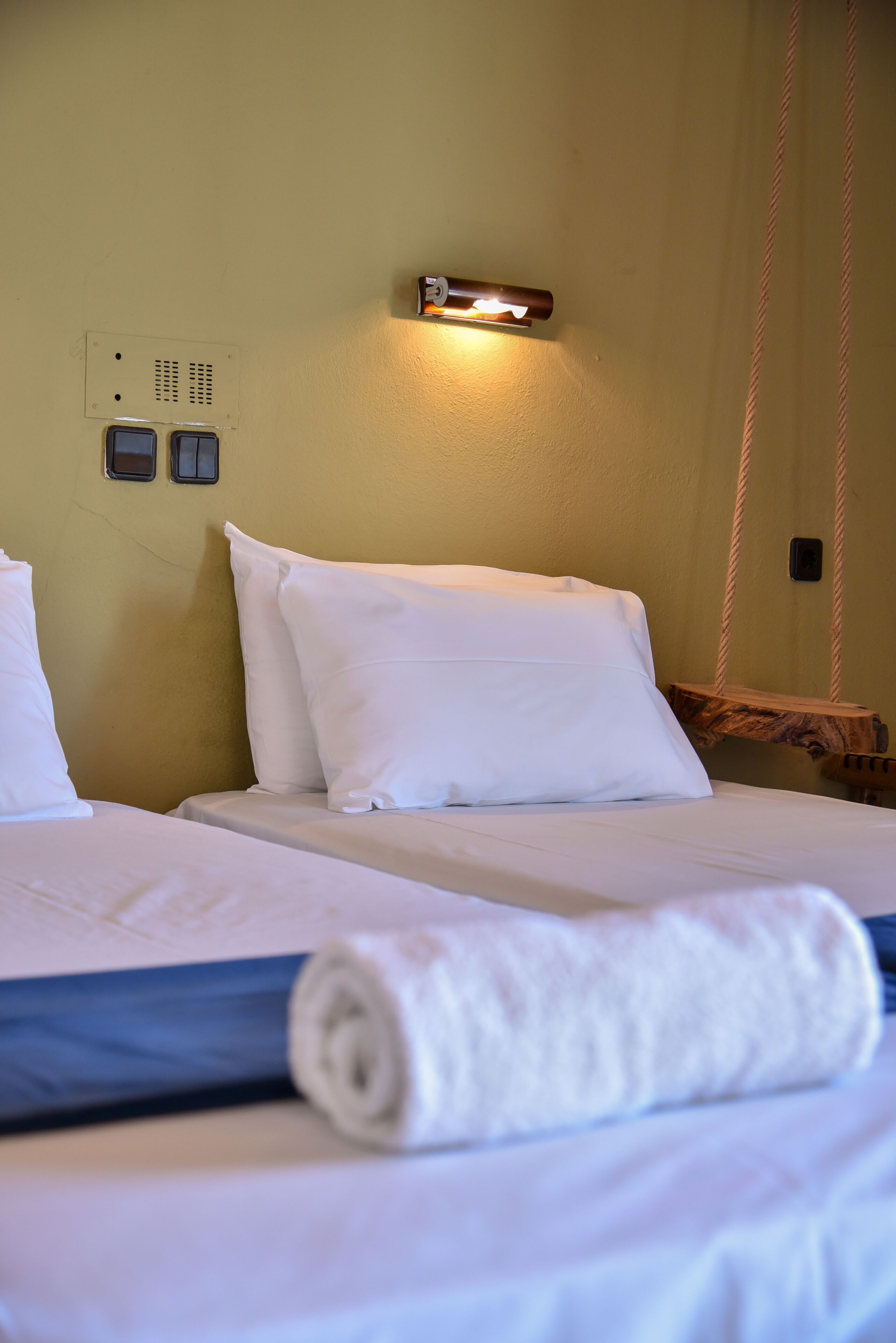 A hotel room with a bed, a wall-mounted light, and a power outlet.