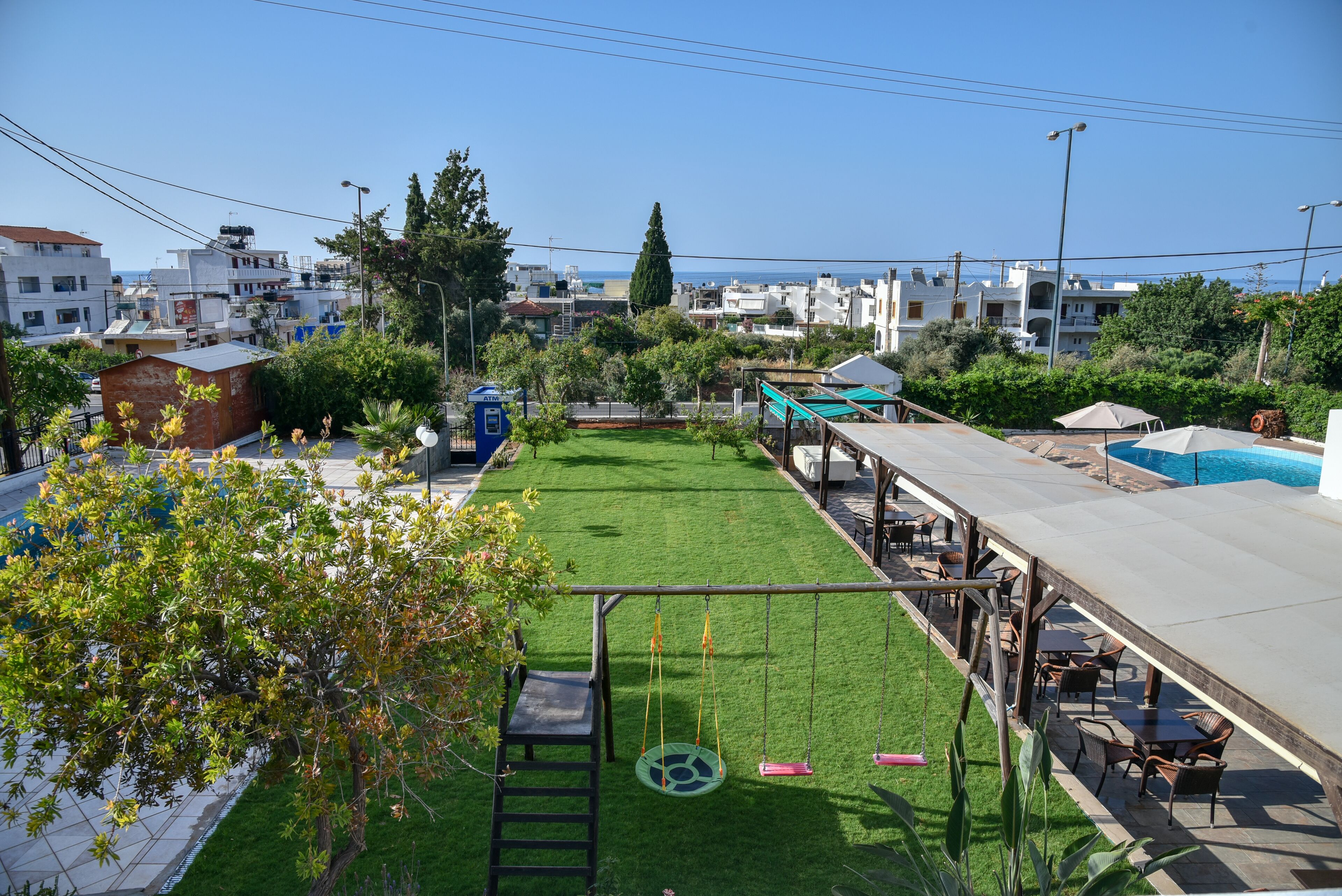 A rooftop garden with a swing set, seating area, and a view of the sea.
