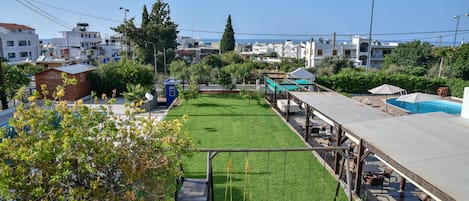 A rooftop garden with a swing set, seating area, and a view of the sea.
