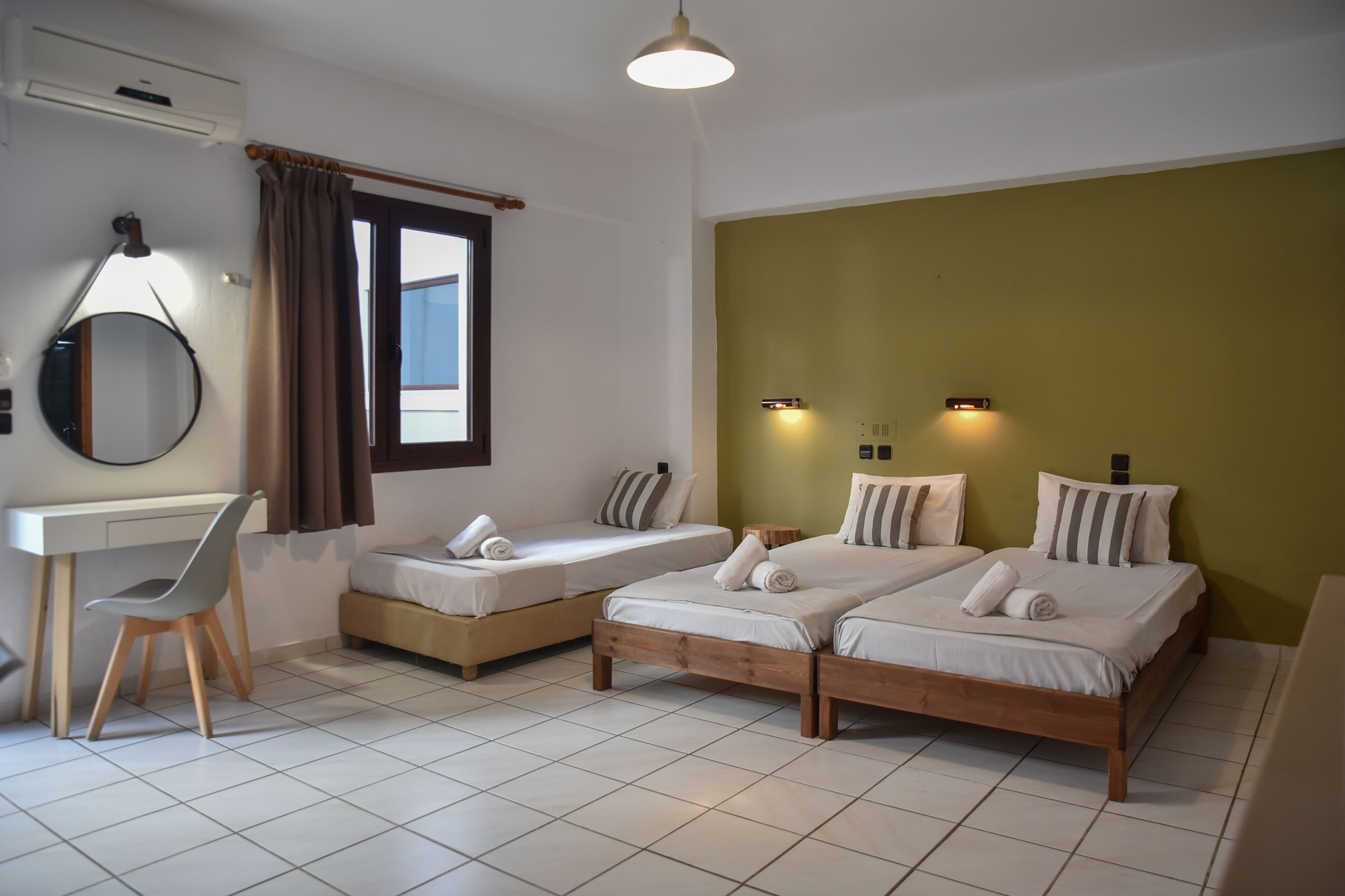 A room with two single beds, a desk, a chair, and a mirror.