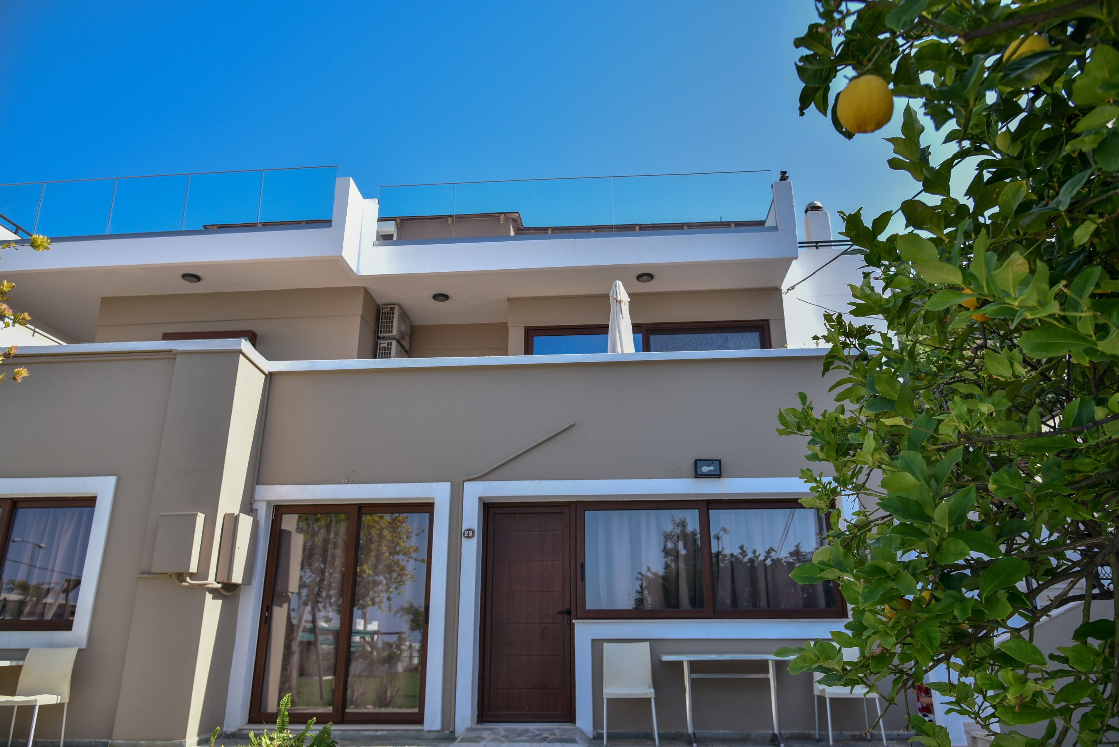 A modern two-story building with a flat roof, large windows, and a balcony.