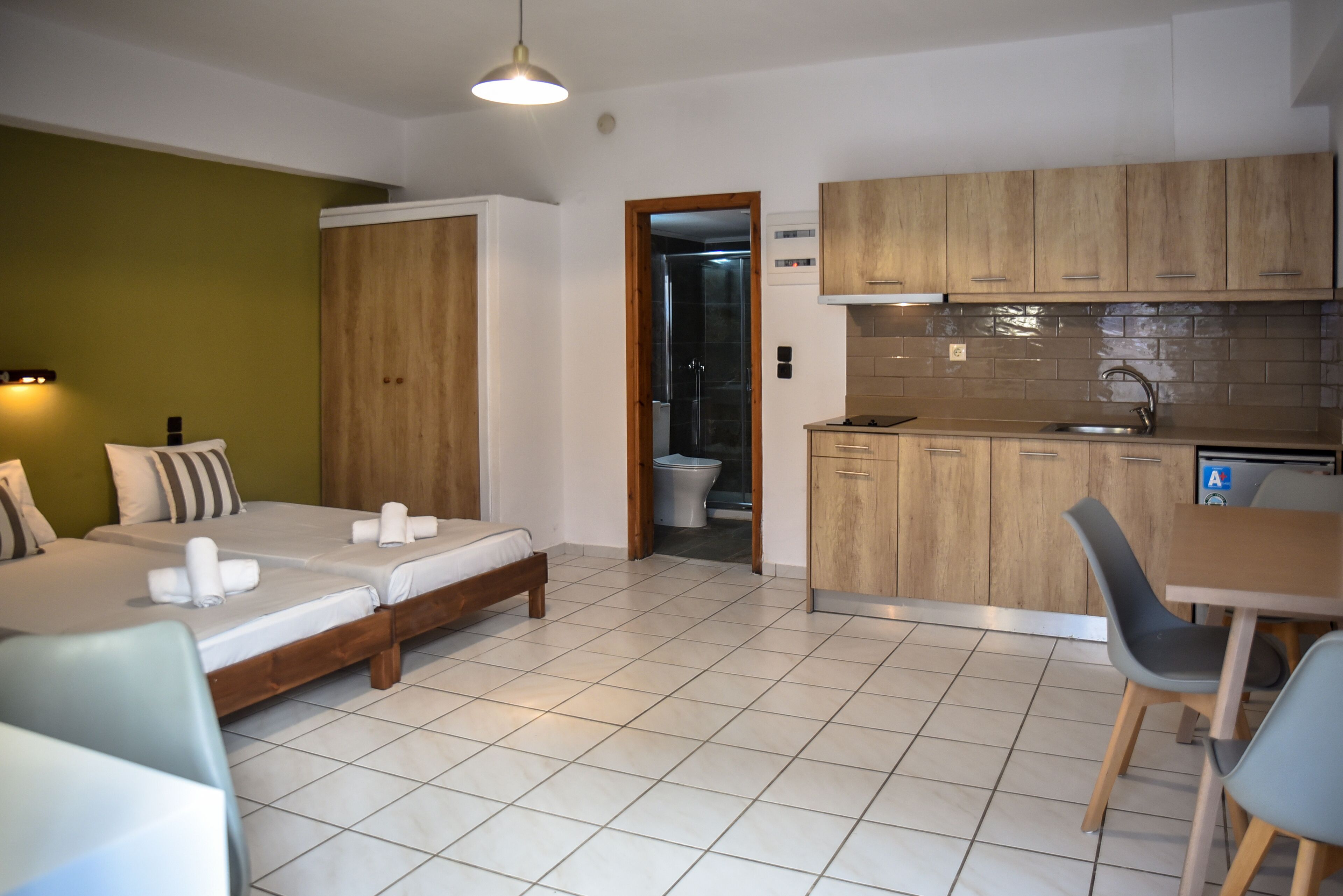 Une chambre d’hôtel de taille réduite, comprenant un lit, une petite kitchenette et une salle de bain.