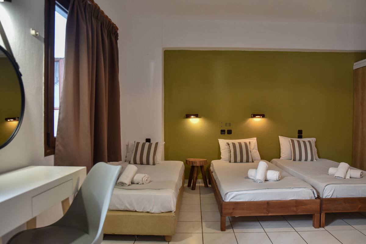 A hotel room with two single beds, a desk, and a chair.