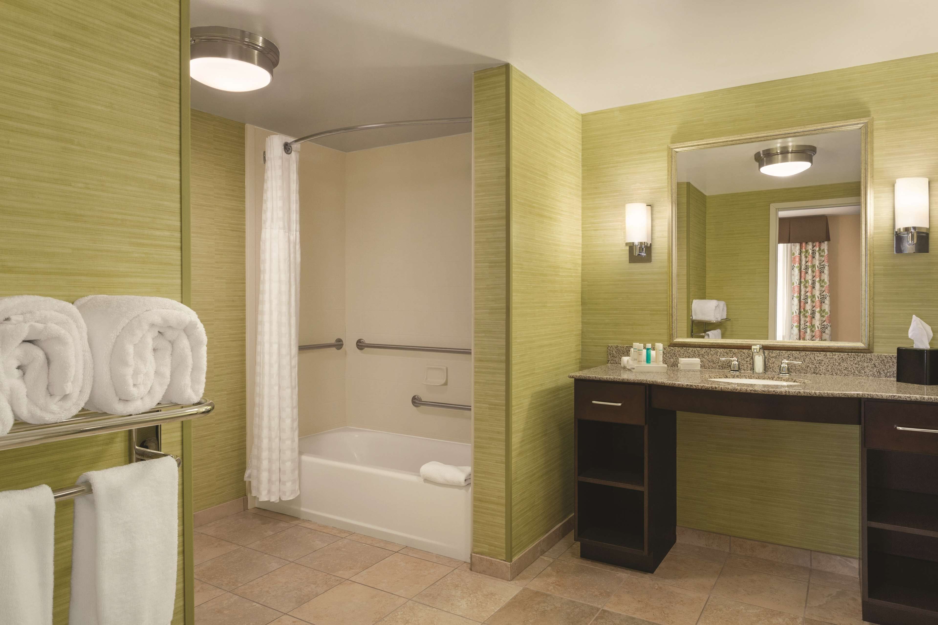 A bathroom with a bathtub, a shower, a vanity with a sink, and a mirror.