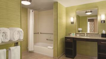 A bathroom with a bathtub, a shower, a vanity with a sink, and a mirror.