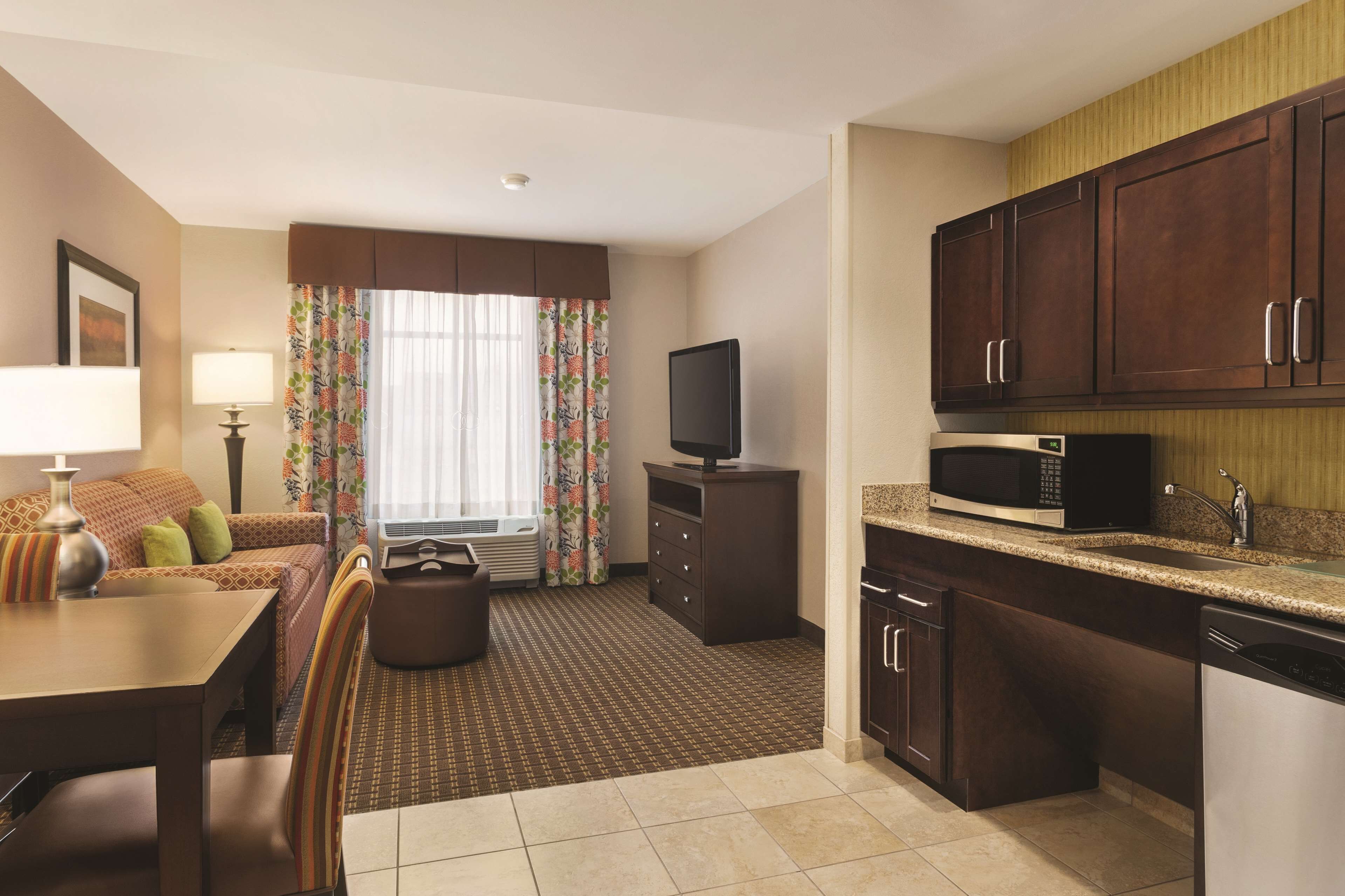 A hotel room with a dining area, kitchenette, and a television.
