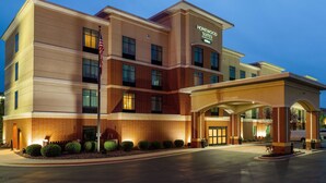 Un hôtel au design moderne, avec une façade en briques et une enseigne bien visible indiquant qu’il s’agit d’un établissement Homewood Suites by Hilton.