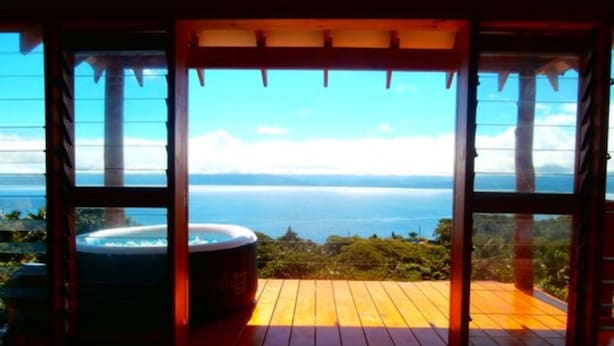 Une terrasse en bois avec un jacuzzi et vue sur l’océan.