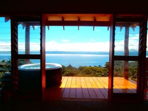 Une terrasse en bois avec un jacuzzi et vue sur l’océan.