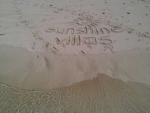 A sandy beach with footprints and the words "sunshine Villas" etched into the sand. - Korovesi Sunshine Villas (Savusavu)