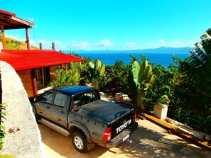 A black Toyota SUV parked in a driveway with a red roofed structure and lush greenery in the background. - Korovesi Sunshine Villas (Savusavu)
