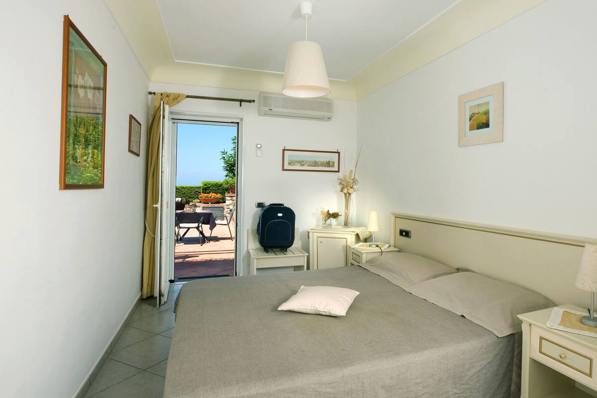 A hotel room with a bed, bedside tables, a lamp, and a suitcase.