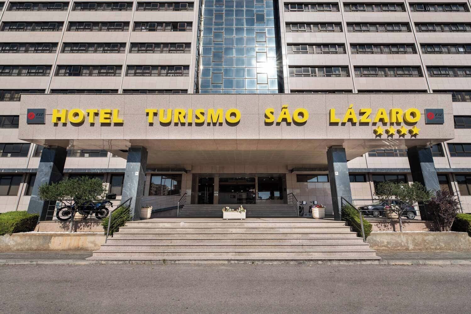 L'ingresso dell'Hotel Turismo São Lázaro, caratterizzato da una facciata moderna, ampie finestre e una segnaletica ben visibile.