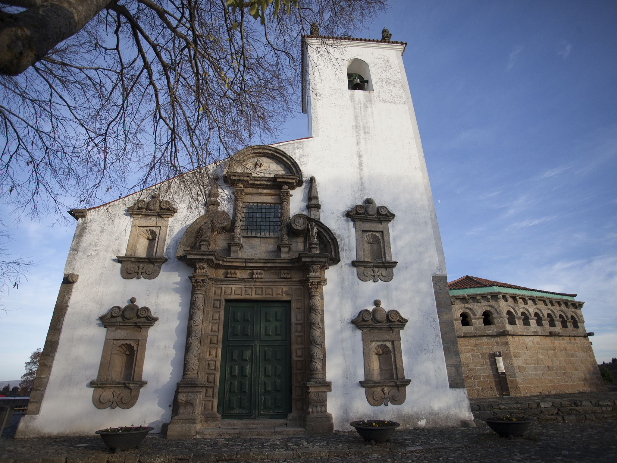 A historic building with a prominent bell tower, a green door, and decorative stonework.