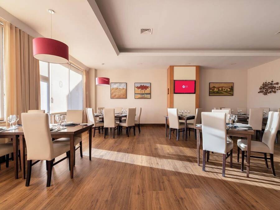 Un vaste espace dédié à la salle à manger, avec de nombreuses tables et chaises, de grandes fenêtres dotées de rideaux et des œuvres d’art accrochées aux murs.