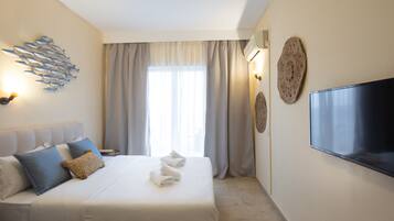 Habitación de hotel con una cama grande, televisión de pantalla plana, un cuadro colgado en la pared y una ventana con cortinas.