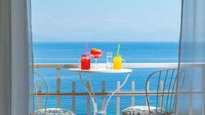 A balcony with a table holding two drinks and a glass, overlooking the sea. - Aurora Beach Hotel (Corfu)
