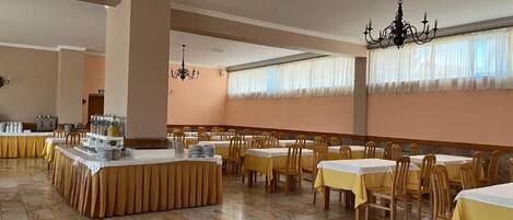 Un comedor con varias mesas, sillas y una mesa de buffet.