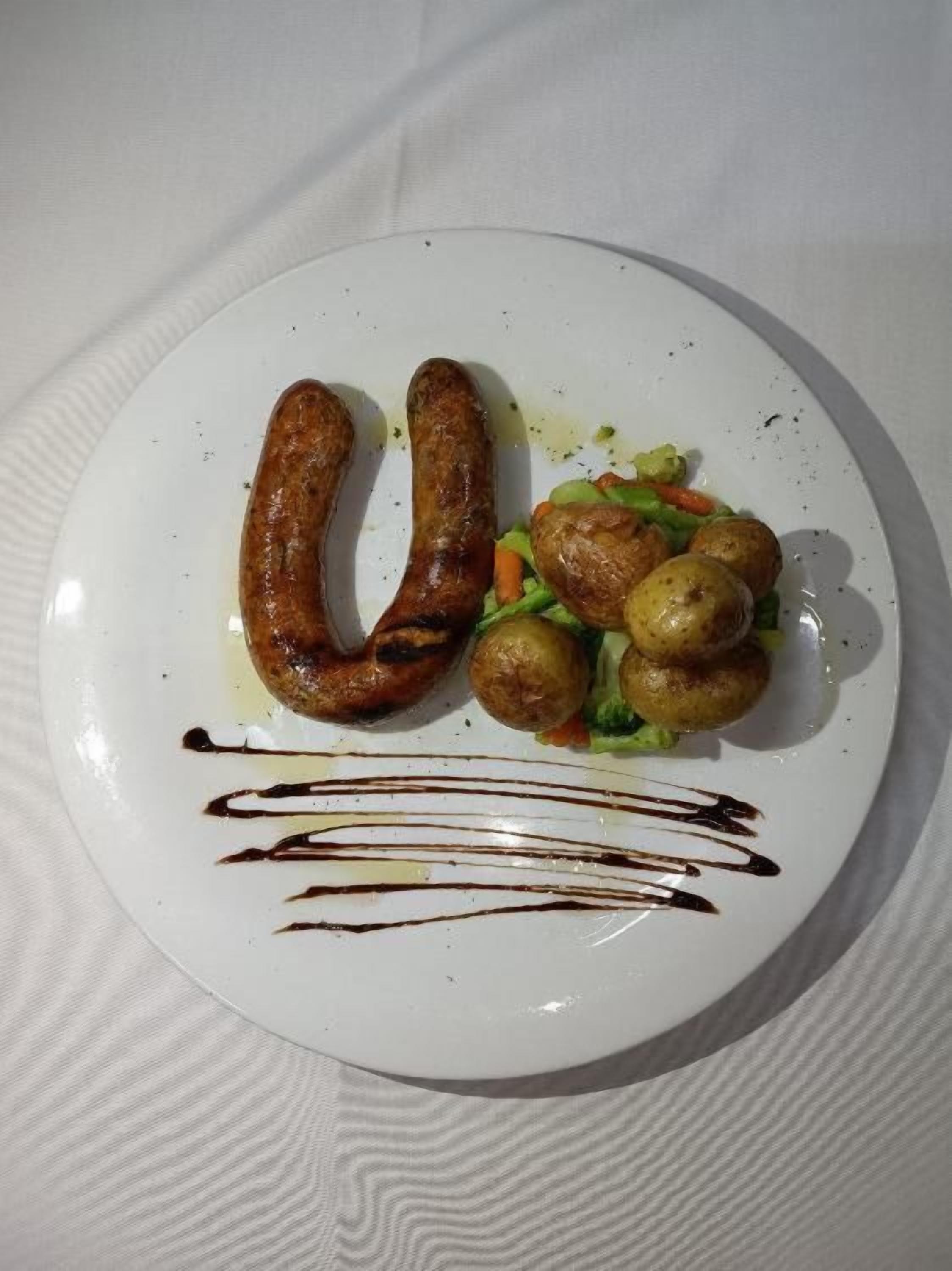 Un plato con salchichas, patatas y verduras.