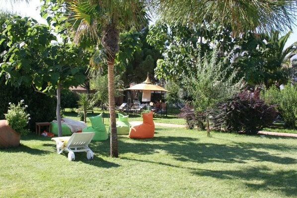 A garden with a gazebo, green and orange seating, and a palm tree.