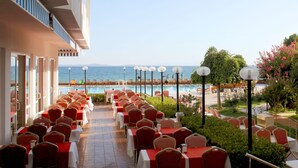 A dining area with tables and chairs arranged for guests, overlooking a pool and the sea. - Hotel Rena (Ayvacik)