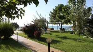 A pathway leading to a grassy area with trees and a view of the sea. - Hotel Rena (Ayvacik)