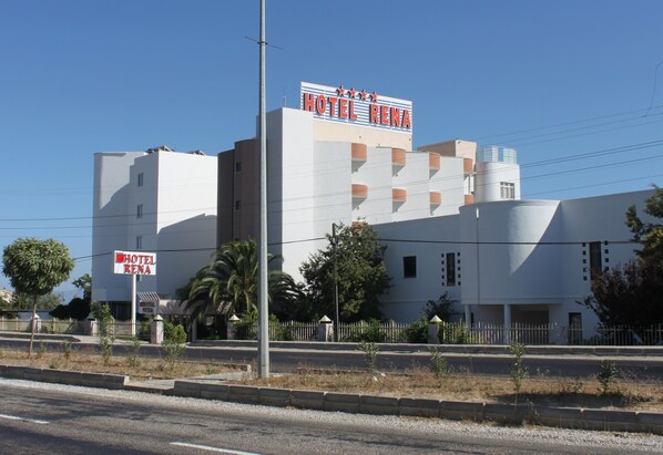 A multi-story building with a sign reading "HOTEL RENA" and a smaller sign below it.