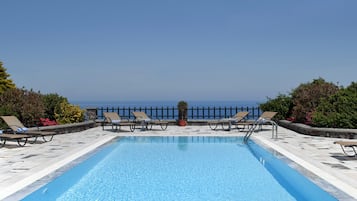 Una piscina al aire libre, sombrillas, sillones reclinables de piscina