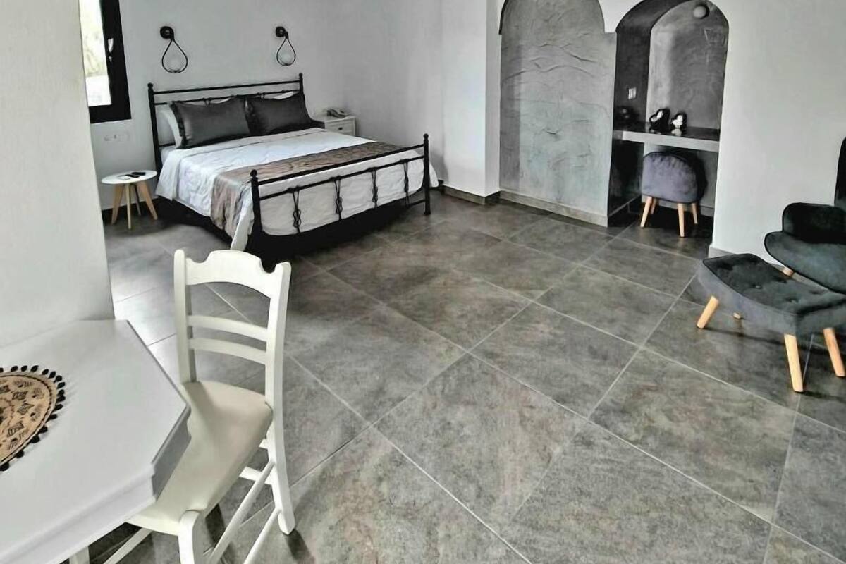 Un dormitorio moderno con cama, escritorio y silla. Hay dos puertas arqueadas que dan a otra habitación.